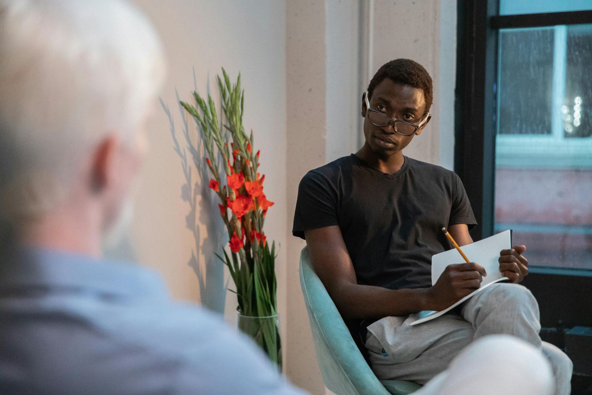 Attentive black man writing in notebook while sitting with client